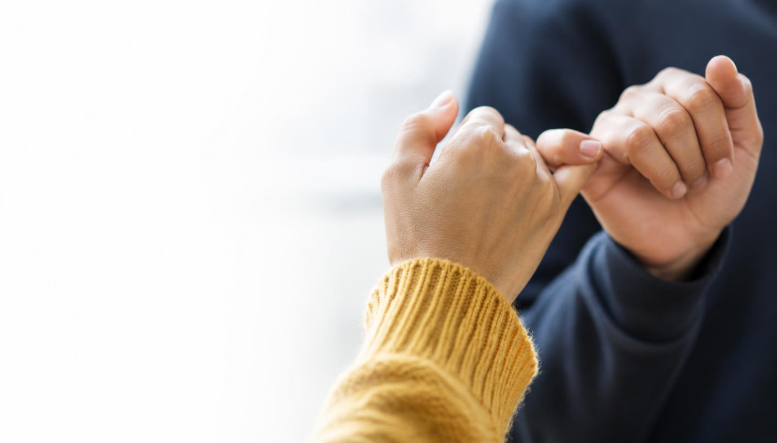 Two hands making a pinky promise, symbolising trust